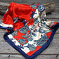 Red, white, and blue patterned silk scarf on wood.