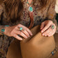 Woman holding cowboy hat, wearing turquoise jewelry, lifestyle image.