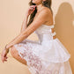 Woman in white floral dress, squatting.