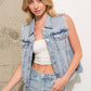 Woman wearing a denim vest and white top.