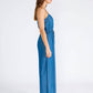 Woman in a blue denim jumpsuit, standing sideways.