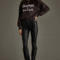 Woman in sweatshirt and black pants and boots.