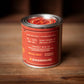 Red candle tin on wood surface.