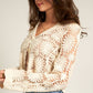 Woman wearing a cream crochet cardigan and jeans.
