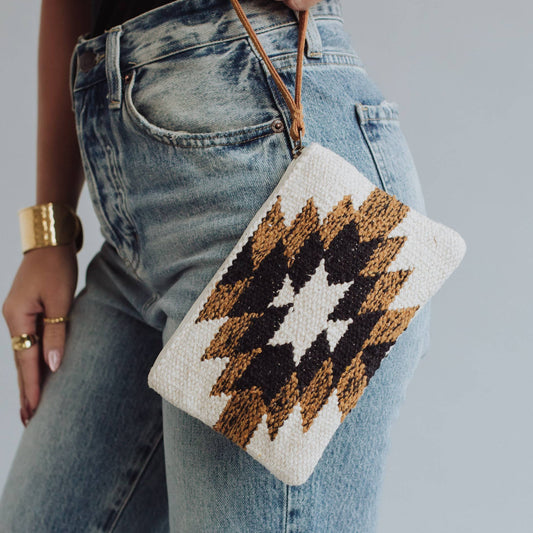 Woman wearing jeans holding patterned clutch.