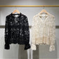 Two lace blouses hanging on a rack.