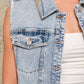 Woman wearing a denim vest and white top.