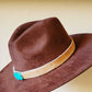 Brown cowboy hat with fur band and turquoise accent.