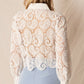 Woman in white lace shirt, blue pants.