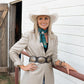 Vintage cowgirl with fringe scarf, jade wild rag, holding horses.