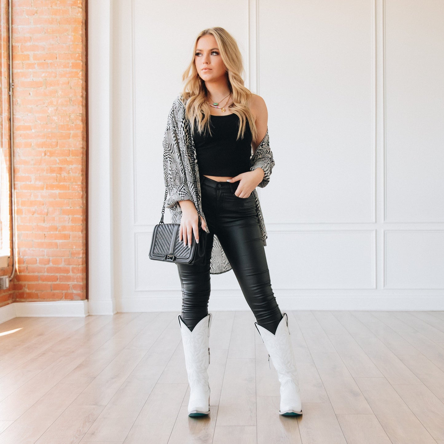 Woman in Smokeshow outfit, black pants, white boots, and cardigan.