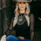 Woman in cowboy hat, mesh top, and jeans.