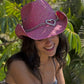 Woman smiling, wearing pink heart-adorned cowboy hat