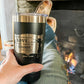 Person holding a black tumbler with etched design.