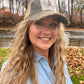 Woman in hat smiling outdoors.