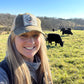 Woman smiling in a field with black cows.