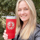 Woman smiling, holding a red tumbler with a logo.