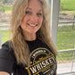 Woman with long blonde hair smiling, wearing a black t-shirt.