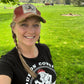 Woman in hat and shirt smiling in a field.